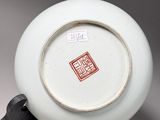 a white plate with a red design on it on a stand