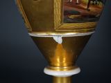 a gold vase with a picture on it on a stand