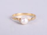 a gold ring with a white pearl on it