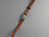 a close up of a watch on a gray surface with a wooden strap