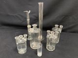 four clear glass beaks and a glass pipe with a black background