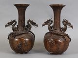 une paire de vases en bronze ornés de têtes de dragon, posés sur une table