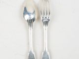 two silver spoons and a fork on a white surface
