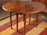 a round table with a wooden top on a striped rug