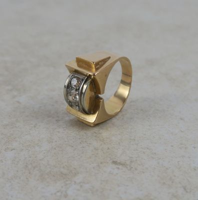 un gros plan d'une bague en or et diamants posée sur une table
