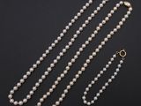 a white pearl necklace with a gold clasp on a black background