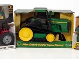 three toy tractors in boxes on a white surface