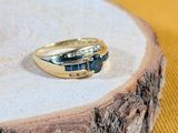une bague en or sertie de deux pierres bleues, posée sur un morceau de bois