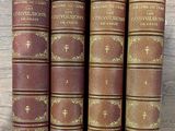 a set of four old books sitting on top of a wooden table