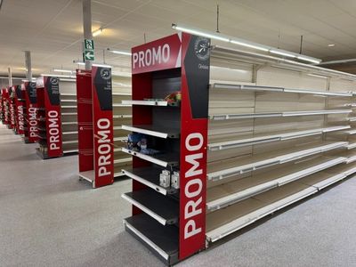 de nombreuses étagères vides dans un magasin, sur lesquelles on peut lire « prono prono »