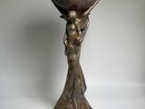 bronze statue of a woman holding a large bowl on her head