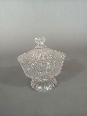bonbonnière en verre transparent avec un couvercle bombé, posée sur un support gris