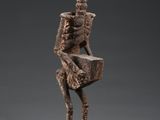 une statue représentant un squelette assis sur un bloc de bois