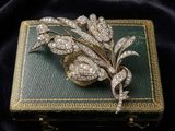 a gold and diamond broochle on a black velvet background