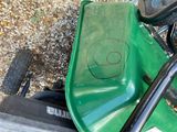 a green lawn mower with a smiley face drawn on it