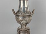 an antique silverplated urn on a stand with a lion head on it