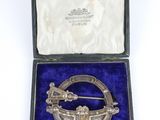 a silver broochle in a velvet case with a blue velvet lining