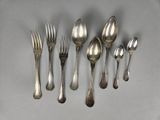 six spoons and a fork are arranged in a row on a table