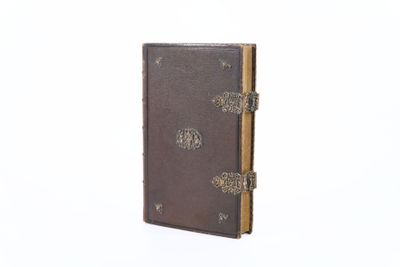 un vieux livre à la couverture brune posé sur une surface blanche