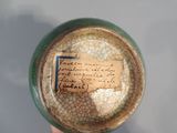a person holding a small bowl with writing on it