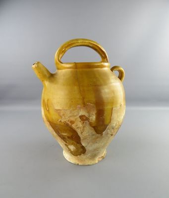 a yellow vase with a handle sitting on a table