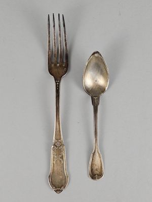 deux cuillères et une fourchette en argent sur une surface blanche