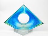 une sculpture en verre bleu percée d'un trou circulaire au milieu