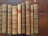 many old books lined up in a row on a table