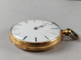 a gold pocket watch with a white face on a table