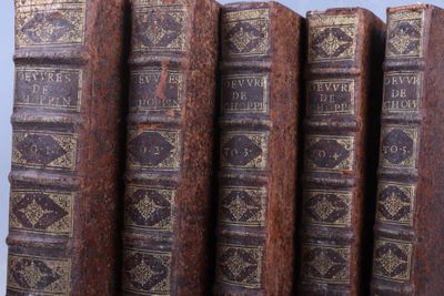 Plusieurs vieux livres sont empilés les uns sur les autres, alignés en rangée.
