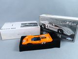 une maquette orange d'une voiture de course devant une boîte