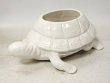 une petite jardinière en forme de tortue blanche posée par terre