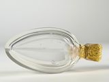clear glass bottle with gold decoration on top on white surface