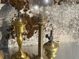 trois bougies en laiton posées sur une table, à côté d'un vase de fleurs