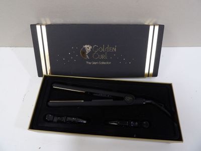 a black box with a gold trim and a black curling brush in it