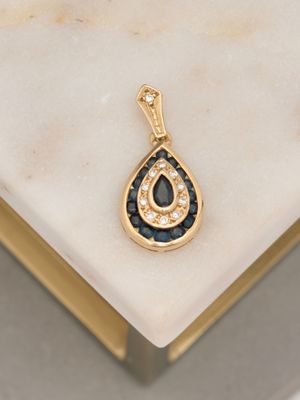 an image of a diamond and sapphire tear pendant on a marble surface