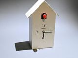 a small white clock with a red bird on it