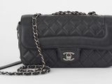 un sac Chanel noir muni d'une bandoulière en chaîne, sur fond blanc