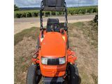 an orange tractor parked in a field on a cloudy day