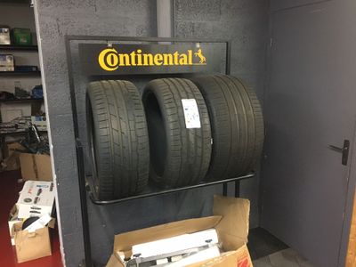 Deux pneus sont empilés sur un chariot dans un garage.