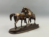 sculpture en bronze représentant deux chevaux, posée sur un socle en bois, sur fond blanc