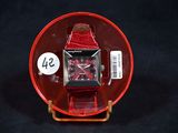 a red watch sitting on a red plate with a price tag