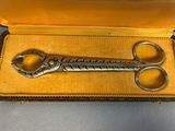 a gold case with a pair of scissors inside of it