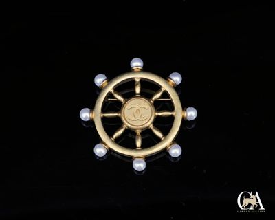 un gros plan d'une broche en or et perles sur fond noir