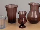 three vases and a glass sitting on a table