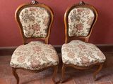 deux chaises aux assises recouvertes d'un tissu à motifs floraux, posées devant un mur rouge
