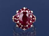 un gros plan d'une bague sertie d'un rubis et de diamants sur un fond bleu