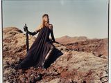 photograph of a woman in a long black dress sitting on a rock with a sword