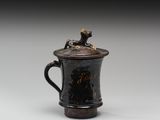 une image représentant une tasse noire sur laquelle est posé un chien