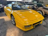 a yellow sports car parked in a lot next to other cars